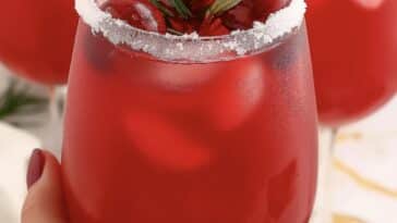 Refreshing holiday cocktail garnished with cranberries and rosemary